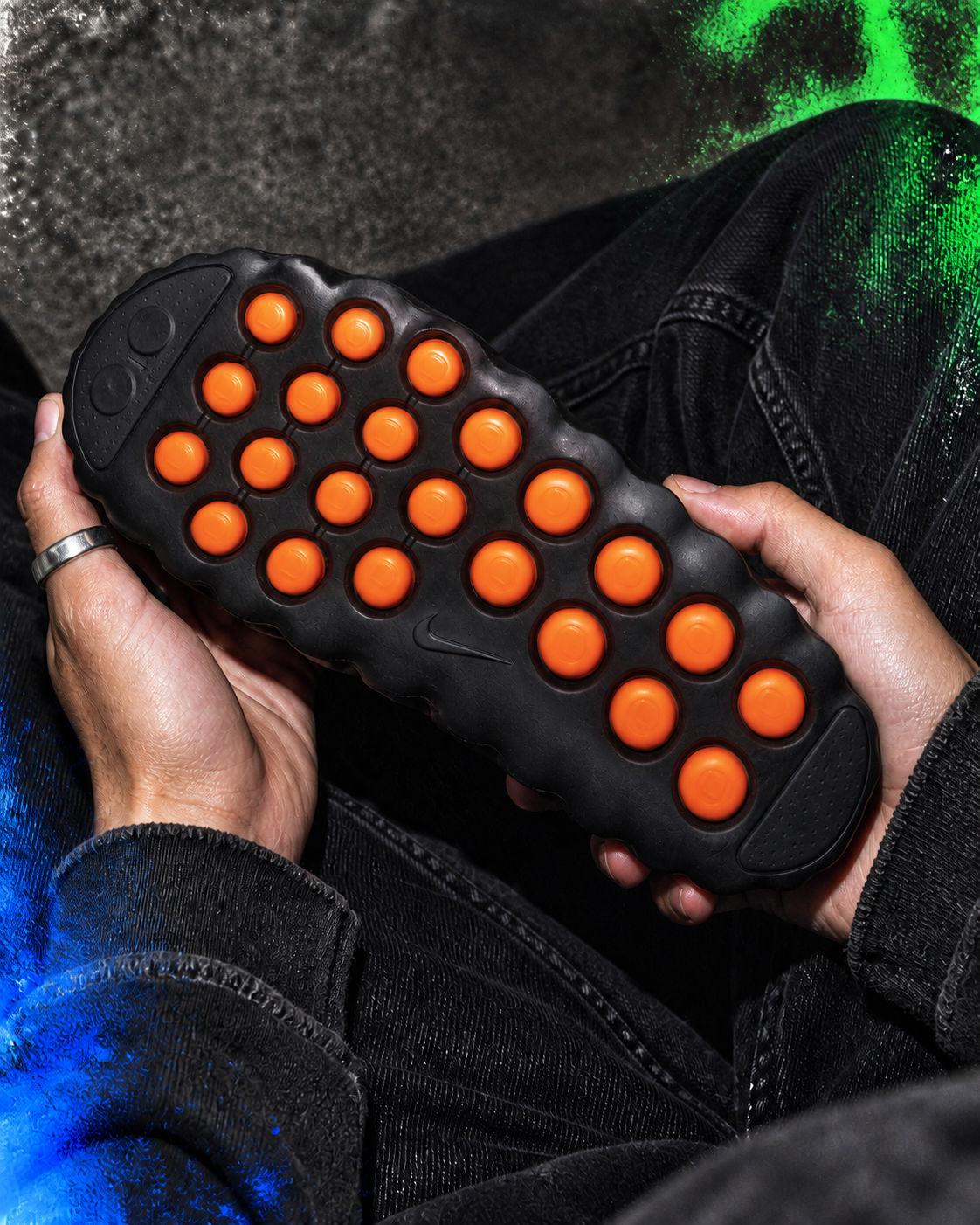 La semelle à capsules orange d'une Nike Mind 001 est inspectée avant l'achat